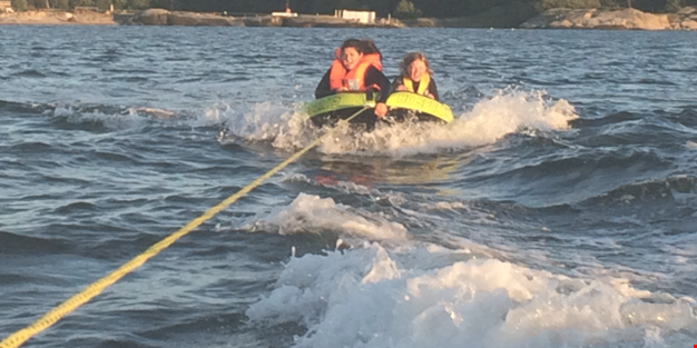 Två personer åker i en uppblåsbar ring efter en båt.